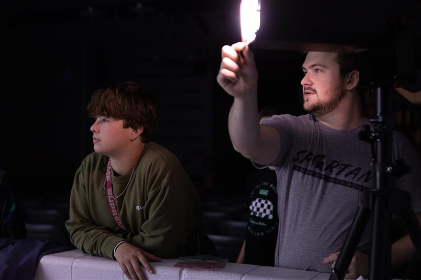 A teacher uses a stage light